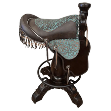 Load image into Gallery viewer, The Mustang Saddle Barstool features embossed turquoise leather, full-grain leather panels, and a hand-forged medallion on a 180° swivel wood base. A handcrafted Western saddle barstool celebrating the artistry and heritage of the American West.