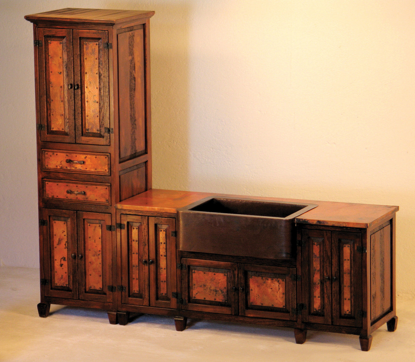Upgrade your kitchen with a handcrafted copper sink and rustic storage cabinets. Featuring hammered copper, wood cabinetry, and iron details, this design combines beauty and function.
