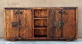 old world credenza Rustic wooden cabinet with metal handles against a beige wall.