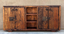Load image into Gallery viewer, old world credenza Rustic wooden cabinet with metal handles against a beige wall.