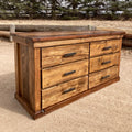 A rustic lowboy dresser made of ponderosa pine with hand forged iron pulls, placed outdoors against a natural backdrop.