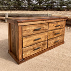 A rustic lowboy dresser made of ponderosa pine with hand forged iron pulls, placed outdoors against a natural backdrop.