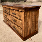 A rustic lowboy dresser made of ponderosa pine with hand forged iron pulls, placed outdoors against a natural backdrop.