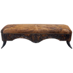 Handcrafted Western bench featuring real cowhide upholstery, carved floral apron, and cowhorn legs. The Santa Petronilla Bench embodies rustic refinement and customizable craftsmanship.