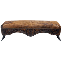 Load image into Gallery viewer, Handcrafted Western bench featuring real cowhide upholstery, carved floral apron, and cowhorn legs. The Santa Petronilla Bench embodies rustic refinement and customizable craftsmanship.