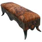 Handcrafted Western bench featuring real cowhide upholstery, carved floral apron, and cowhorn legs. The Santa Petronilla Bench embodies rustic refinement and customizable craftsmanship.