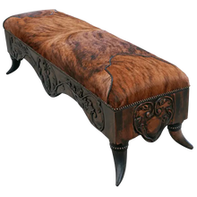 Load image into Gallery viewer, Handcrafted Western bench featuring real cowhide upholstery, carved floral apron, and cowhorn legs. The Santa Petronilla Bench embodies rustic refinement and customizable craftsmanship.