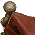 The Bronco Saddle Barstool features a handcrafted full-grain leather saddle seat with cowhide fenders, hand-forged iron medallion, and wood pedestal base. A 180° swivel Western barstool blending authentic cowboy craftsmanship with rustic luxury.