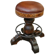 Load image into Gallery viewer, The El Matador Bajo 5 Barstool features brown full-grain leather, hand-tooled accents, and a carved wood base with a forged iron footrest. A 360° swivel and customizable design make it a perfect blend of comfort and craftsmanship.