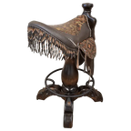 The Chaps Saddle Barstool features full-grain leather, embossed Western patterns, copper conchos, and a 180° swivel wooden base. A handcrafted Western saddle barstool that celebrates cowboy craftsmanship and the artistry of the American frontier.