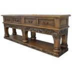 Handcrafted Spanish colonial console with baroque floral scroll carvings, forged iron handles, 4 drawers, platform base & antique finish. Customize your luxury Western décor piece.
