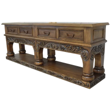 Load image into Gallery viewer, Handcrafted Spanish colonial console with baroque floral scroll carvings, forged iron handles, 4 drawers, platform base &amp; antique finish. Customize your luxury Western décor piece.