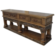 Load image into Gallery viewer, Handcrafted Spanish colonial console with baroque floral scroll carvings, forged iron handles, 4 drawers, platform base &amp; antique finish. Customize your luxury Western décor piece.