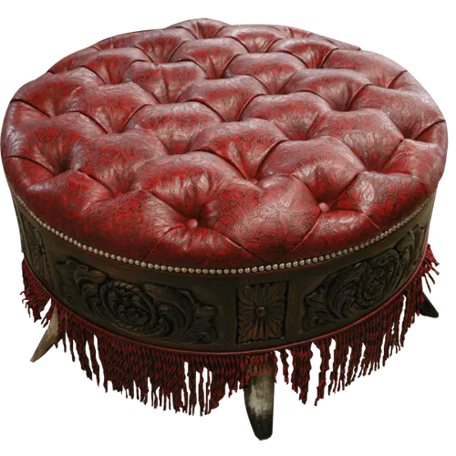 Handcrafted red leather ottoman with carved wood base, nailhead trim, and fringe detailing. The Coronado Ottoman blends Western luxury with timeless artisan craftsmanship.