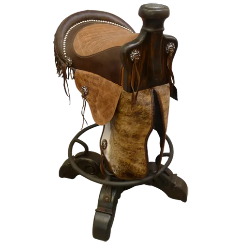 The Saddle Barstool features a handcrafted genuine leather cowboy saddle seat with cowhide fenders, hand-forged conchos, and a turned wood base with iron footrest. A 180° swivel Western barstool blending craftsmanship, comfort, and heritage.