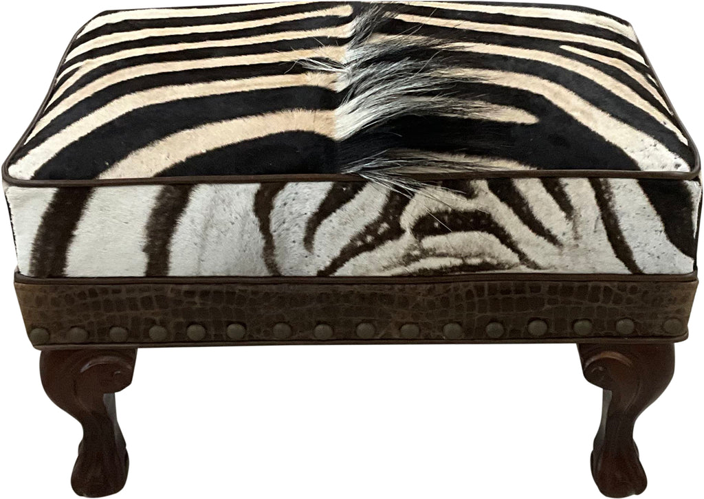 Luxury zebra hide ottoman with authentic zebra hide and mane top, Gator Walnut leather rail, nailhead trim, and carved wood legs. Western safari accent stool 27" x 17".