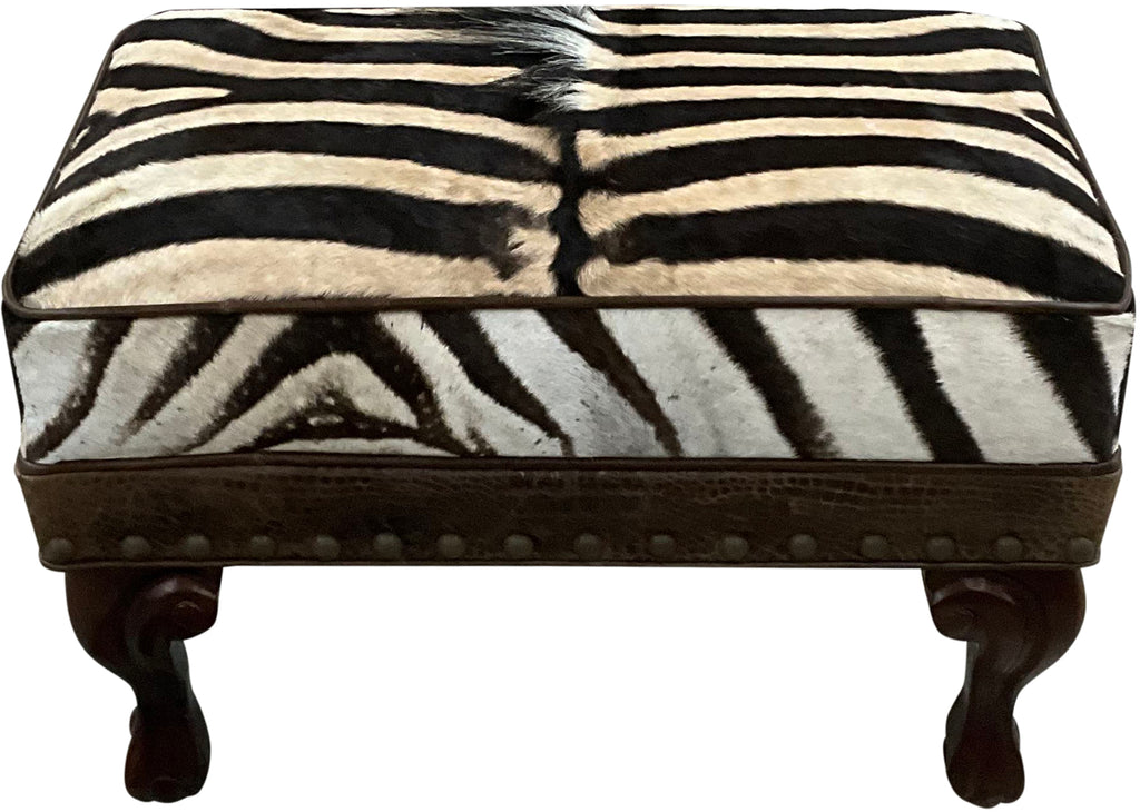 Luxury zebra hide ottoman with authentic zebra hide and mane top, Gator Walnut leather rail, nailhead trim, and carved wood legs. Western safari accent stool 27" x 17".